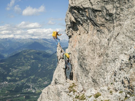 Trekking in Tirolo, Austria: allo Jesacherhof Due arrampicatori con caschi e zaini su una roccia ripida in montagna