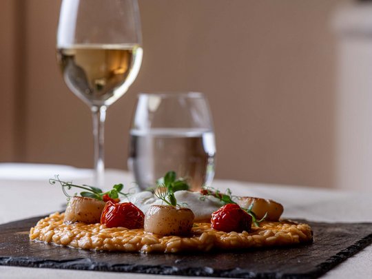 Jesacherhof: Gourmethotel in Österreich Risotto mit Jakobsmuscheln und Cherrytomaten auf schwarzer Steinplatte