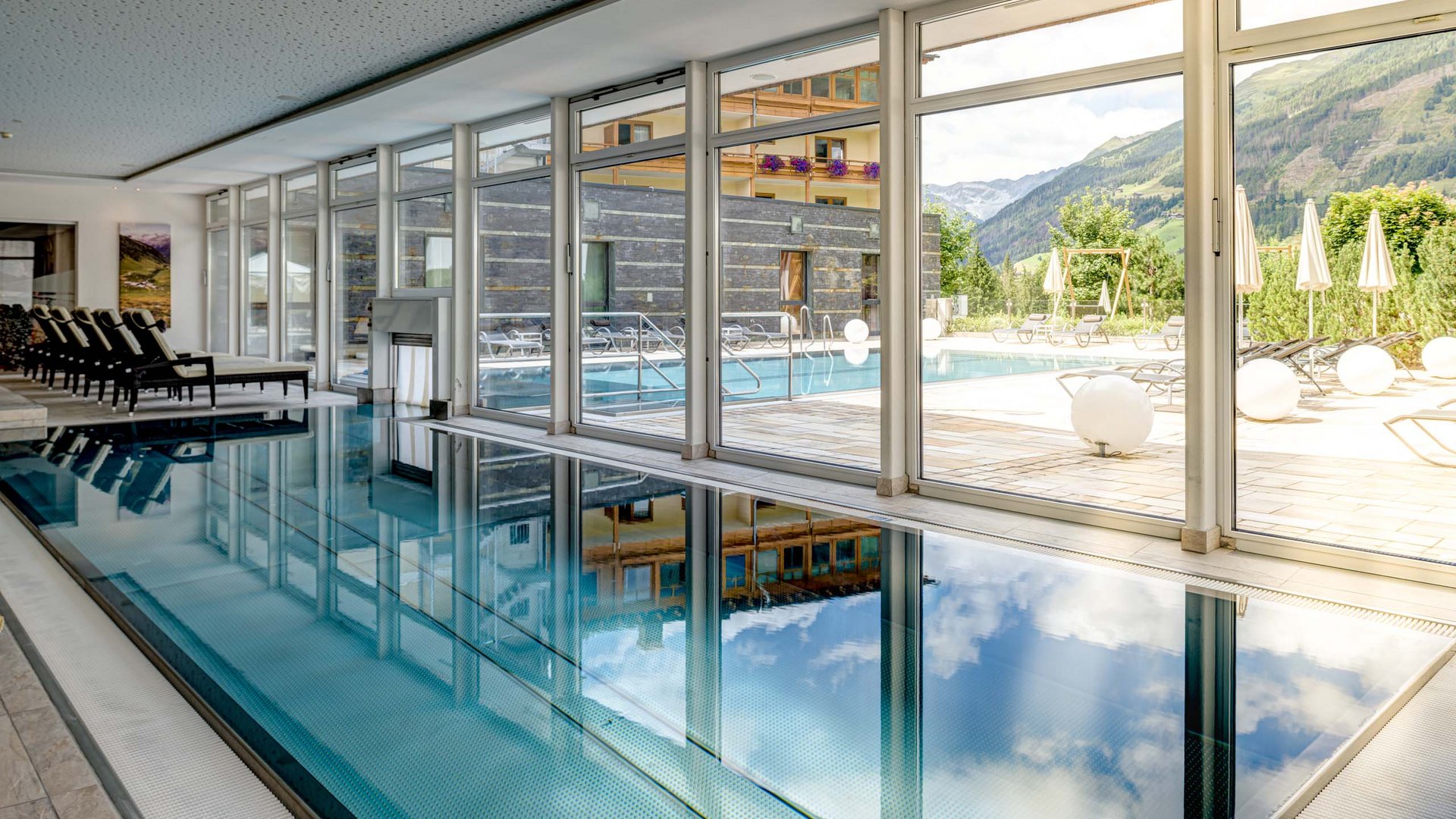 Wellnesshotel im Defereggental: Wohlfühlurlaub vom Feinsten Innenpool mit Fensterblick auf Außenschwimmbecken und Berglandschaft
