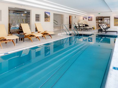 Area adults only del nostro wellness hotel in Austria Piscina interna con lettini e quadri di montagne alle pareti