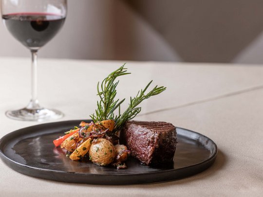 Jesacherhof: Gourmethotel in Österreich Gegrilltes Steak mit Bratkartoffeln und Rosmarin, daneben Glas Rotwein