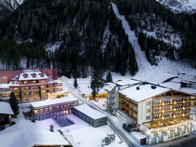 Freude verschenken: unser Hotel in Osttirol mit Wellness Winterliche Alpenhotels mit Schnee, Wald und Berg im Hintergrund bei Abendlicht